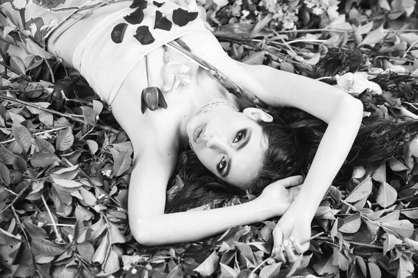 Vrouw met modieuze make-up met bloemen op donkergroene bladeren — Stockfoto