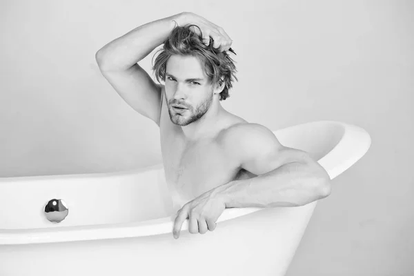 Мужчина с мускулистым телом сидит в белой ванне — стоковое фото