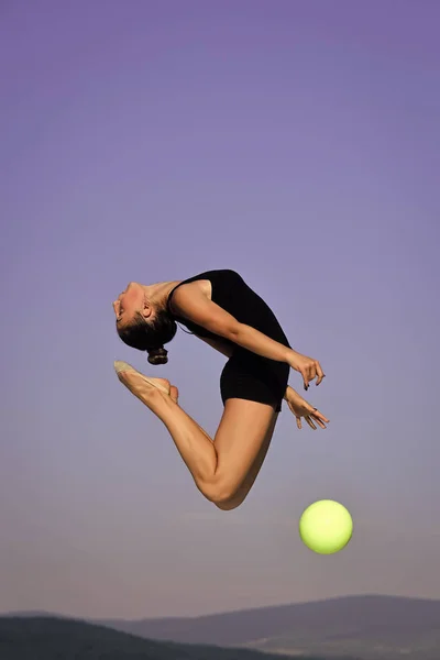 青い空を背景に緑のボールを持つ女性の体操 — ストック写真