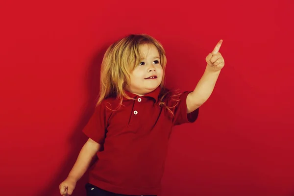 Piccolo ragazzo felice che punta il dito su sfondo rosa — Foto Stock