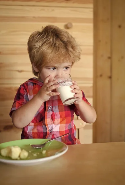 Desayuno, mañana, familia. Niño pequeño come plátano y bebe leche . — Foto de Stock