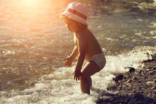 Хлопчик грає з водою на фоні природного пляжу — стокове фото