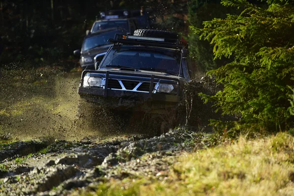 Koncept konkurence, energie a motorsport. Auto racing na pozadí přírody na podzim. Terénní vozidla nebo Suv překonává překážky. Auto racing v podzimním lese. — Stock fotografie