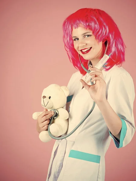 Ευτυχισμένος νοσοκόμα χαμογελά σε κόκκινη περούκα σε ροζ φόντο — Φωτογραφία Αρχείου