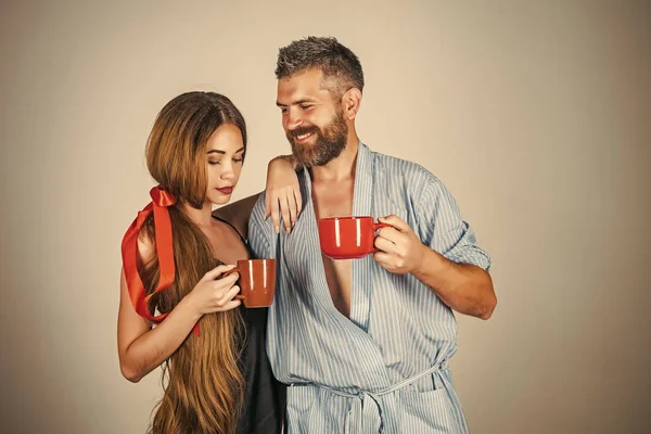 family of man and woman with red milk cup. Refreshment and energy, break. Perfect morning with coffee. man and girl with mulled wine on grey background. couple in love drink morning coffee or tea.