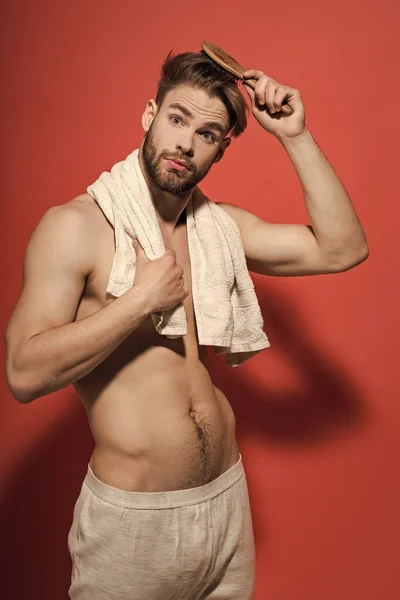 Guy brush hair with hairbrush on red background