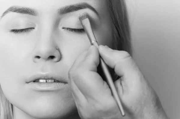 Chica consiguiendo sombra de ojos en polvo en los párpados con cepillo —  Fotos de Stock