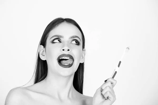 Chica con dientes frenos y cepillo, tiene maquillaje de moda —  Fotos de Stock