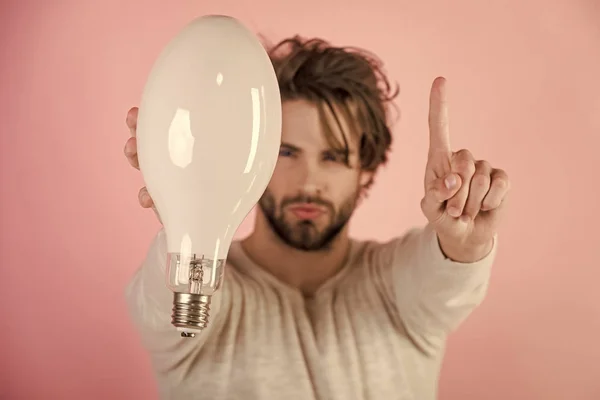 Серйозна людина з розмитим волоссям тримає велику лампу, ідею, рішення — стокове фото