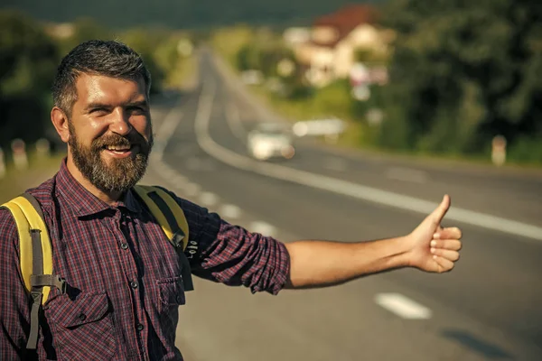 Hombre con mochila feliz autostop en el camino — Foto de Stock
