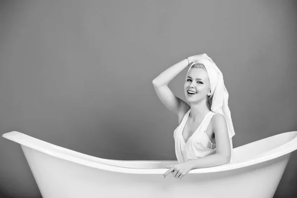 Mujer sonriendo con turbante de toalla sentado en una bañera blanca —  Fotos de Stock