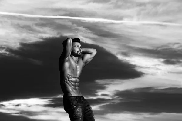 Muscoloso uomo con muscolo busto su nuvoloso tramonto cielo sfondo — Foto Stock