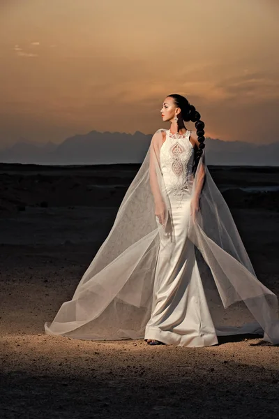 Kum tepeleri üzerinde dağ manzarası içinde gelin