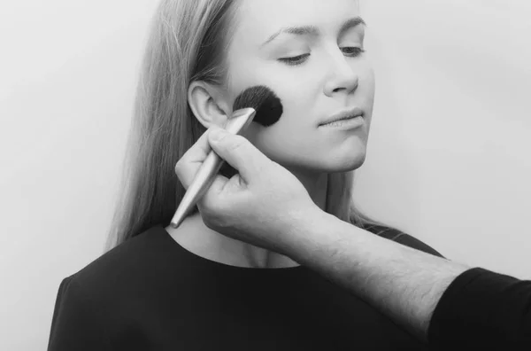 Ragazza ottenere polvere sul viso con pennello trucco in mano — Foto Stock