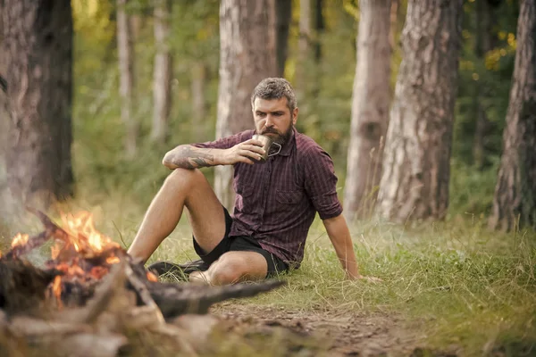 Homme voyageur boire du thé à la flamme du feu de camp — Photo