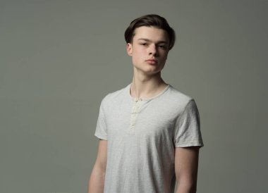 Işık gömlek, gri arka planda emin yüz adam. Maço şık uzun saç kesimi ile. Erkeklik kavramı. Adam kameraya, kopya alanı arıyor yüzündeki pürüzsüz bir cilt ile.