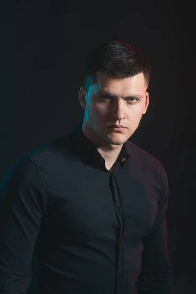 Man with serious young face on dark backgroud. Man wear fashionable black shirt — Stock Photo, Image