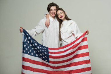 Kız ve erkek kardeşim bizi bayrak, bağımsızlık günü kutlama aile tutan. Güzel genç kardeşler birbirlerine gri arka plan üzerinde izole sarılma beyaz kıyafetler içinde