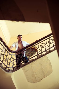 Adam stand merdiven üzerinde yüksek. İşadamı tırmanmaya merdivenler. Seksi maço merdiven üzerinde çıplak gövde ile açık gömlekli. Kariyer, hırs ve başarı kavramı başarı