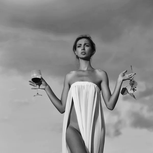 Mooi meisje met glas wijn en druiven over hemel — Stockfoto