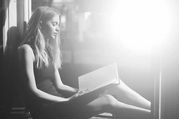 Menina bonita imaginando história com livro em branco na janela aberta — Fotografia de Stock