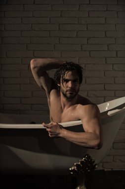 Küvet içinde oturan ıslak saçlı çocuk.