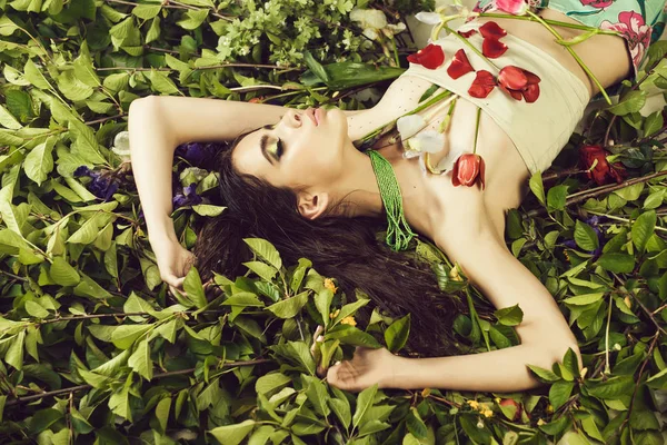 Mujer con maquillaje de moda con flores en hojas verdes — Foto de Stock