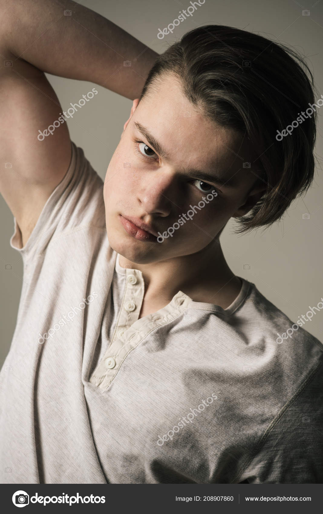 Guy On Confident Face In Light Shirt Touches Hair Grey Background