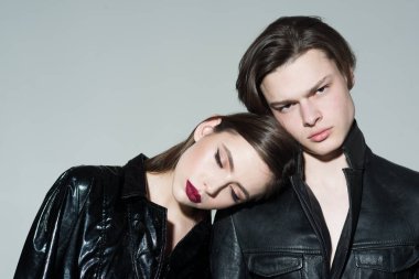 Yalın erkek omuz, gri arka plan üzerinde makyaj kız. Sakin yüzleri moda giysiler giymiş bir kaç. Moda kavramı. İki şık manken moda fotoğraf oturumunda, kopya alanı.