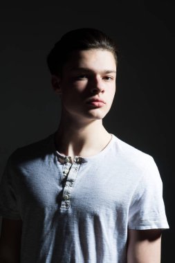 Maço şık uzun saç kesimi ile. Erkeklik kavramı. Pürüzsüz bir cilt ve yüz, kopya alanı üzerinde gölgeler olan adam. Adam kendine güvenen yüzüne ışık gömlek, siyah arka plan üzerinde.