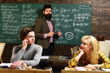 Modern öğretmen hippi matematik formülü ile büyük yazı tahtası üzerinde yazılı. Eğitim ve okuma birlikte lise üniversite öğrencileri Eğitim kavramları sınıf. Öğretmenler itibar altındır.