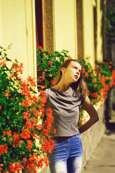 Entzückende, junge Frau, die neben blühenden Blumentöpfen an Fenstern steht — Stockfoto