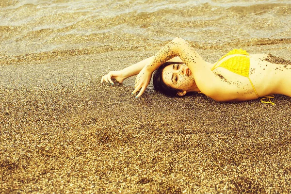Ładna dziewczyna leży w górze żółty strój kąpielowy na plaży — Zdjęcie stockowe