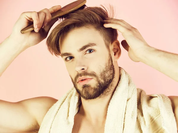 Skäggig man med bad handduk på hals kamning friskt hår — Stockfoto
