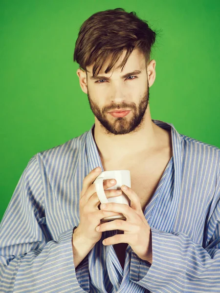 man drinking cup of tea or coffee in robe