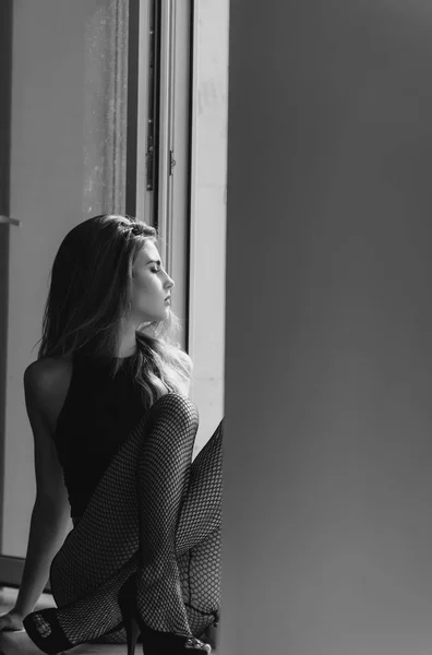 Ziemlich sexy Mädchen sitzt mit Beinen auf Fensterbank — Stockfoto