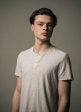 Beyaz genç Çocuk T-shirt gri arka plan üzerinde izole. Uzun saçlı, şevk gençliğin kendine güvenen genç adam portresi
