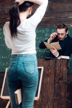 Bacaklarının arasında bir kitap ve bir at kuyruğu yapmak bulanık dönüş geri kız. Profesör duran Kürsüsü, kitap okuma