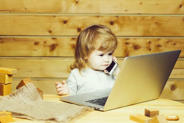 Маленький мальчик с компьютером и телефоном — стоковое фото
