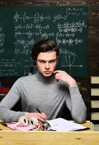 Schüler müssen engagiert und selbstdiszipliniert sein, um ihre Ziele zu erreichen. Selbstbewusster Student, der am Schreibtisch mit dem Laptop ein Buch liest. Lehrer vermittelt Schülern Führungsgefühl. — Stockfoto