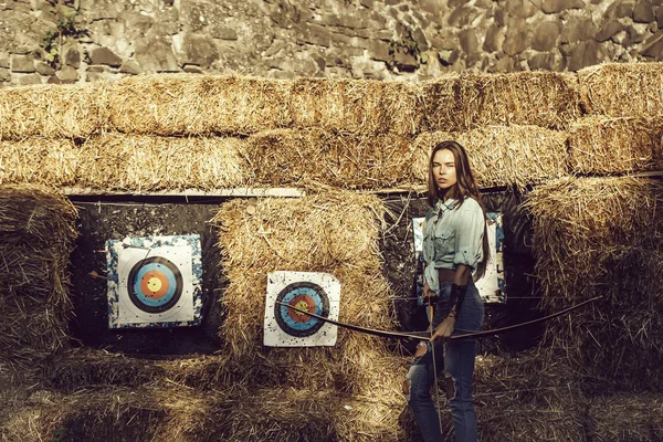 Ragazza sveglia arciere tenendo arco e freccia a bersagli tiro con l'arco — Foto Stock