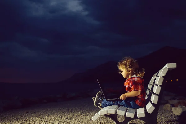 Söt pojke med laptop på stranden — Stockfoto
