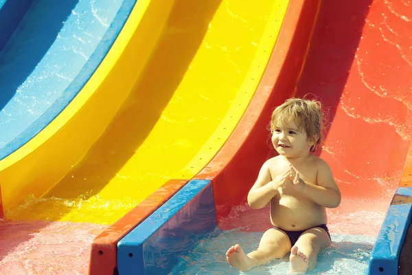 Happy cute baby boy rides from waterslide — Stock Photo, Image