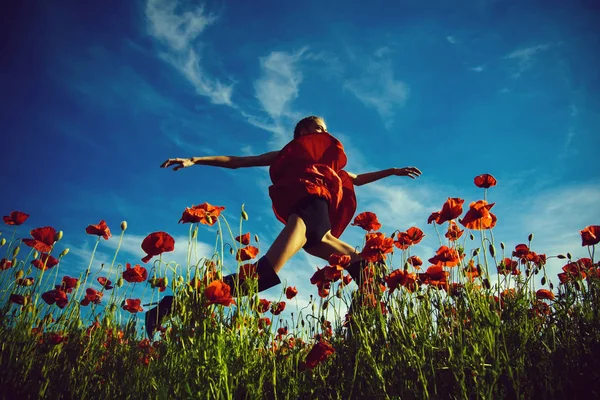 Bella ragazza che salta nel campo di fiori di semi di papavero — Foto Stock