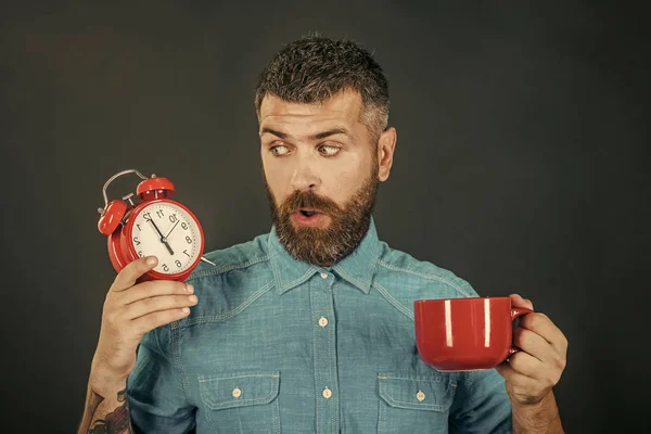 Man drink morning coffee or tea with alarm clock.
