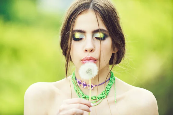 Mulher com maquiagem elegante soprando dente de leão, queda de cabelo — Fotografia de Stock