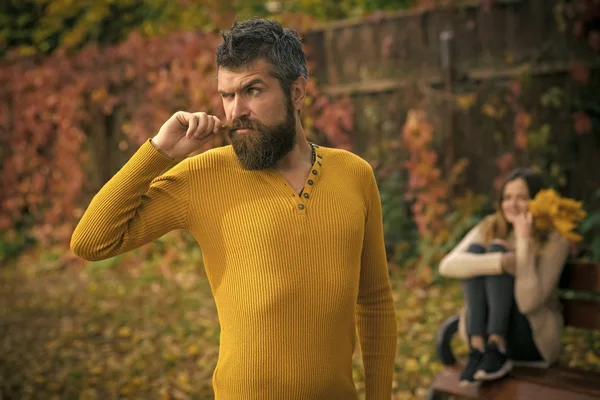 Man with beard and woman with yellow tree leaves.