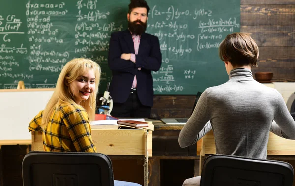 As relações pessoais são fundamentais para o sucesso dos estudantes. Alunos atentos escrevendo algo em seus blocos de notas enquanto sentados em mesas na sala de aula. — Fotografia de Stock