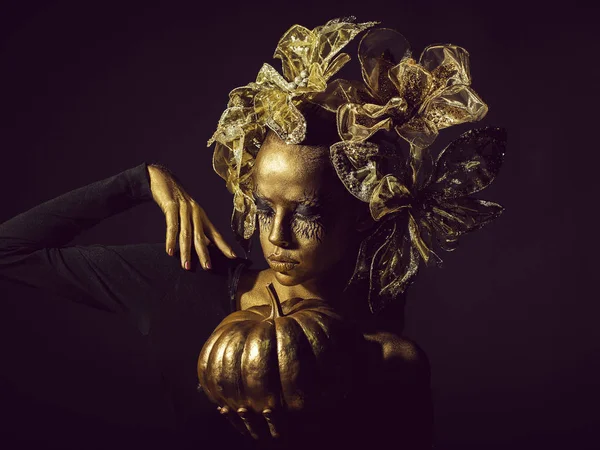 Mulher dourada com abóbora halloween — Fotografia de Stock