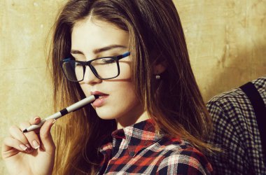 Güzel kız öğrenci ağzına kalem tutan inek bardaklarda